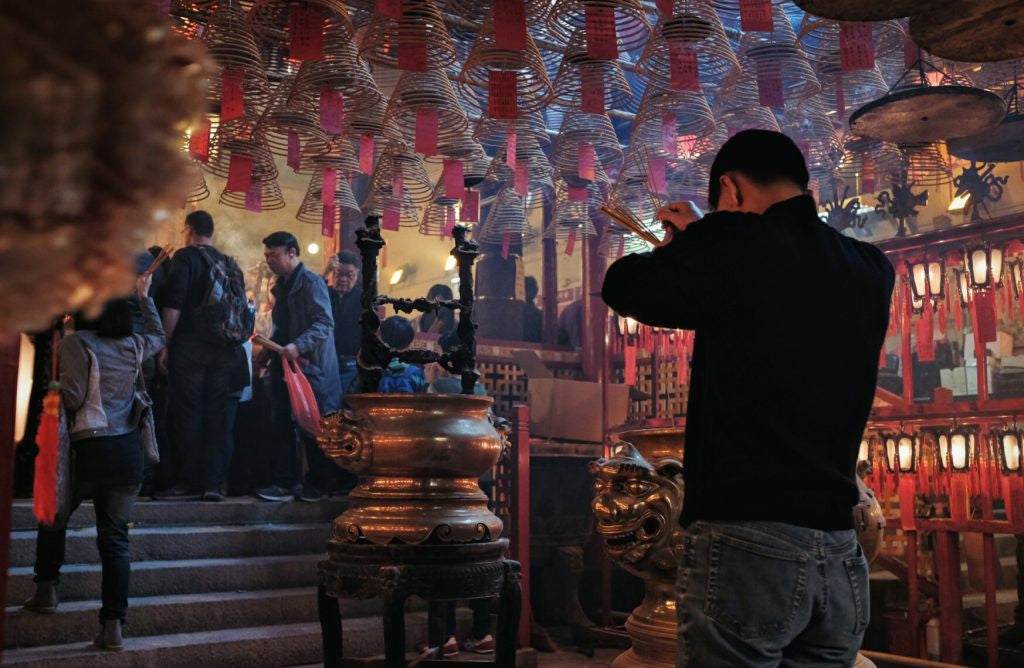 person worshipping at temple using incense