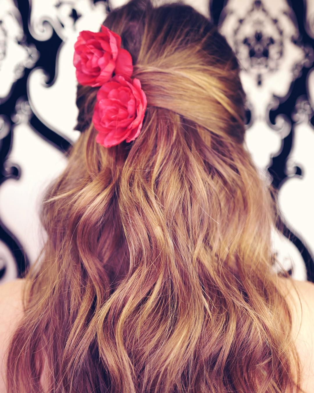 back of womans head with red flowers pinned in it after using TO112 products