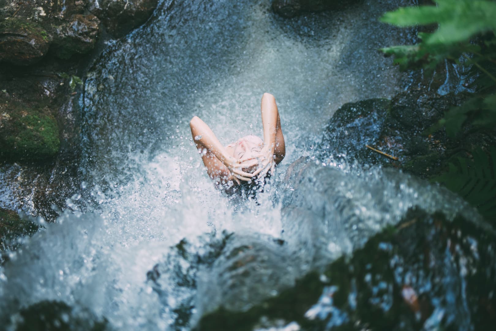 birds eye view of woman bathing under waterfall 