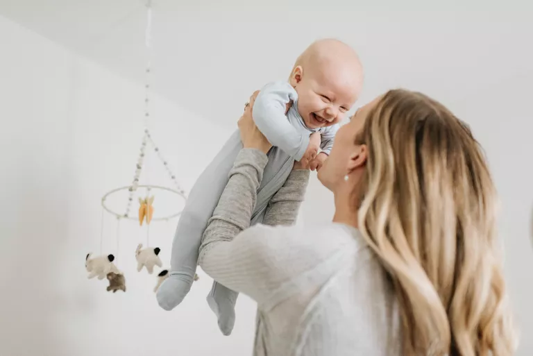 Woman holding her baby in the air with baby laughing