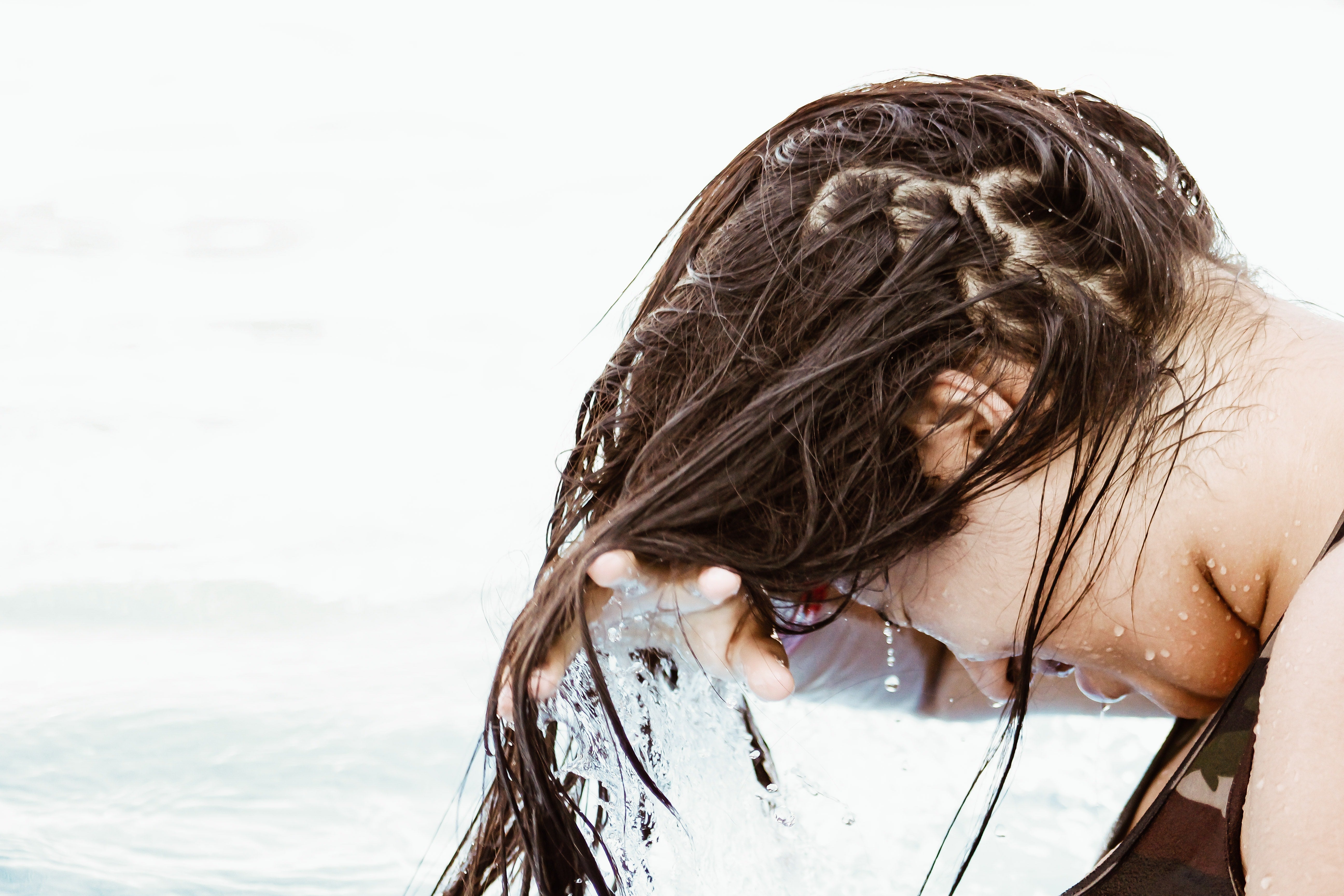 woman washing hair in ocean with TO112 products