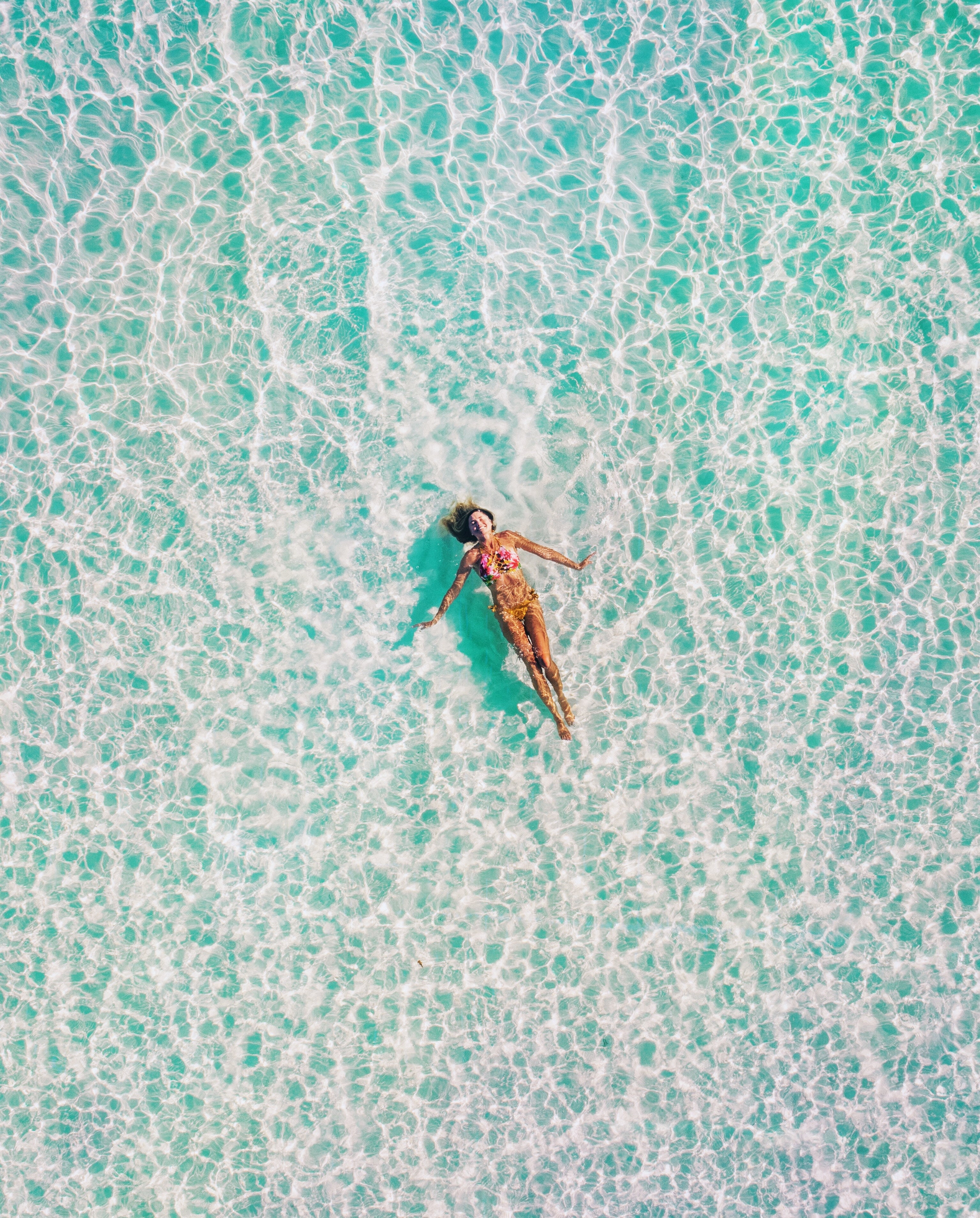 woman floating in ocean from a birds eye view