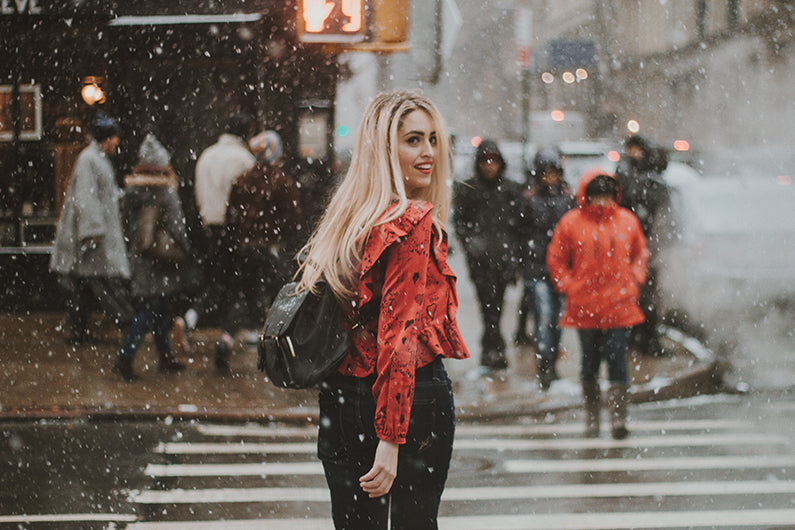 blonde woman in red shirt crossing the road while it snows