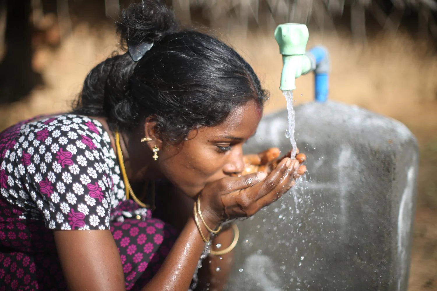 young woman drinking fresh water thanks to the efforts of Water.org and support of brands like TO112