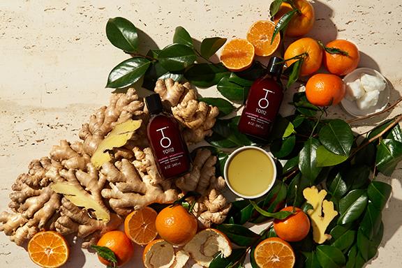 To112 dry shampoo and conditioner on green foliage, slices of clementines, and ginger root